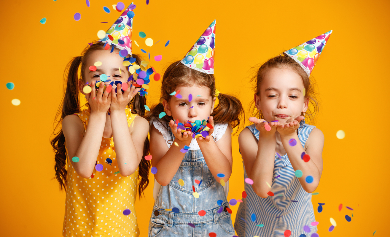 Children blowing confetti in party hats
