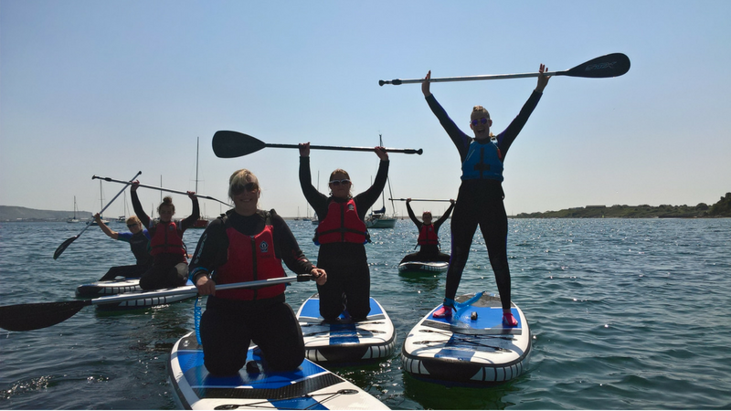 A group of women stand up paddleboarding Weymouth