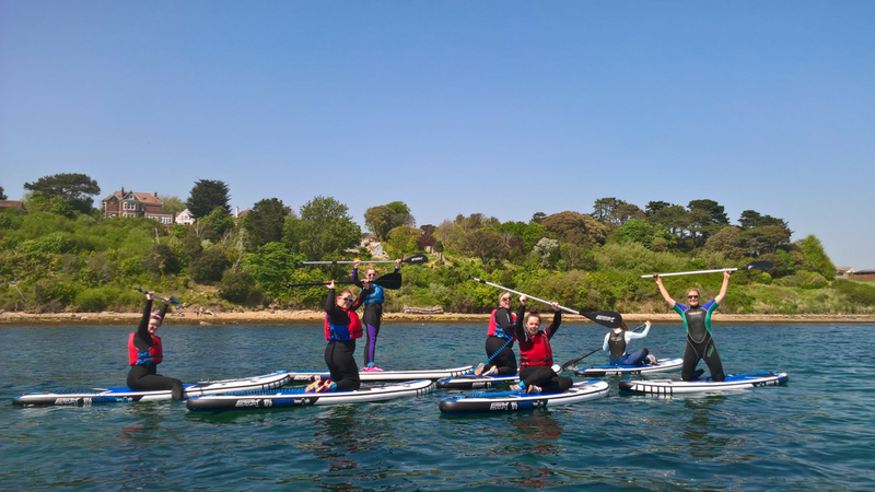 A group of young people stand up paddleboarding