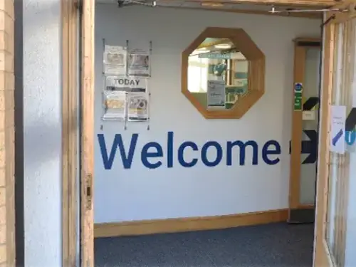 This is a picture of the entrance to the library with the automatic doors open.  There is a welcome sign inside the door.