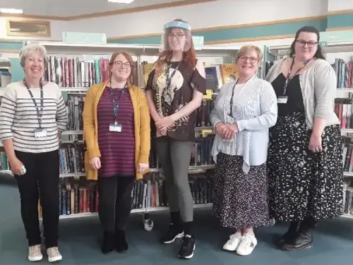 This is a picture of five library assistants standing and smiling at the camera.