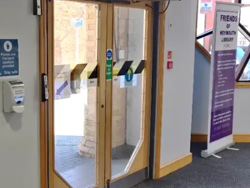 This picture shows the wooden and glass exit doors with a push button to the left side to open the doors.
