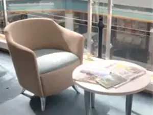 This picture shows a chair to the left side and a small round table to the right with magazines on it.