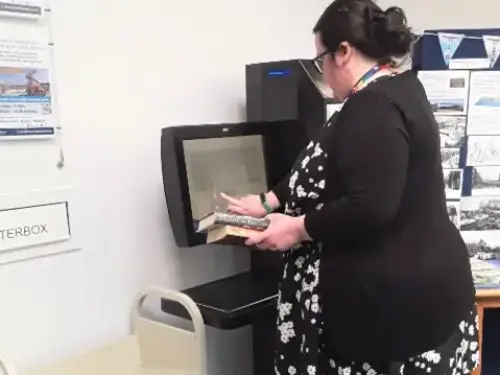 This picture shows a library assistant using the self service machine.