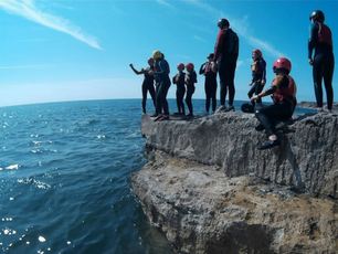 A group of children coasteering on the rocks in Weymouth