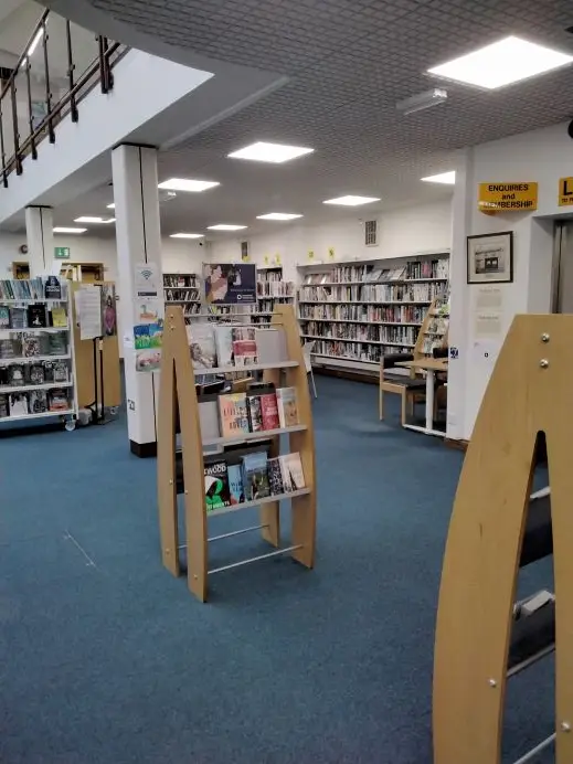 This is a picture of a large room with smaller freestanding shelves of books to the foreground and larger shelves lining the walls behind.
