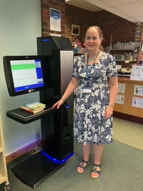 llibrary staff standing next to a book borrowing machine