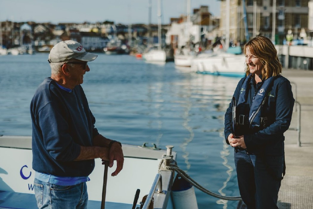 A Dorset Council harbour employee talking to a man stood on a boat.