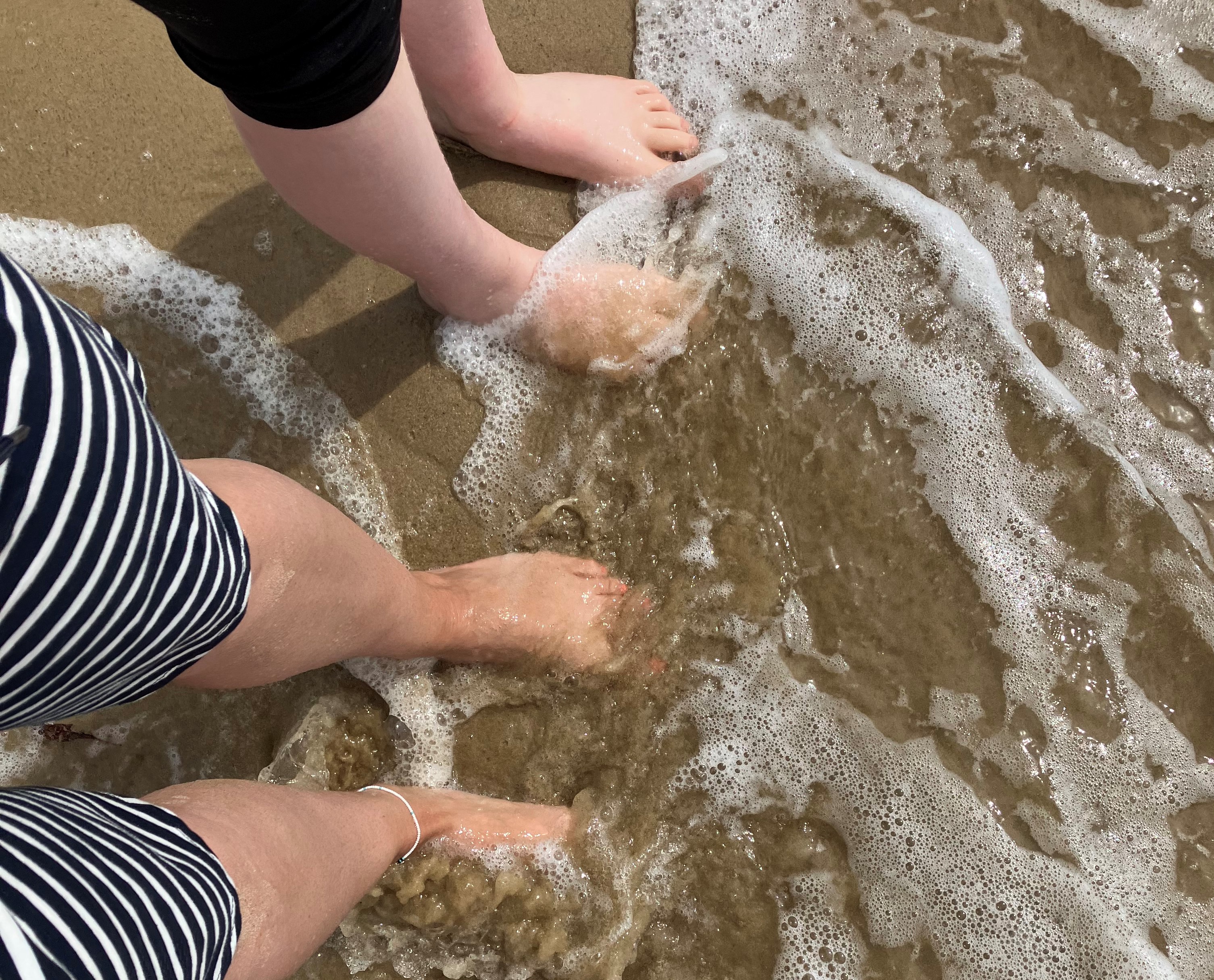 two sets of bare feet in the sea