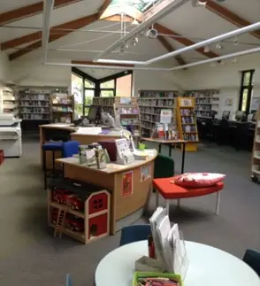 This is a picture of a large room with shelving full of books and chairs here and there.