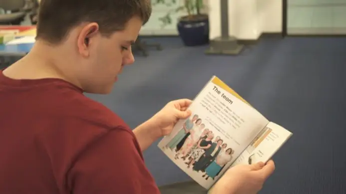 This is a picture of a child sitting in a chair, reading a book.