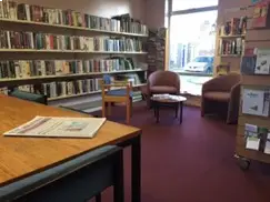 This is a picture of a small round table surrounded by three chairs with book shelves behind the chairs.