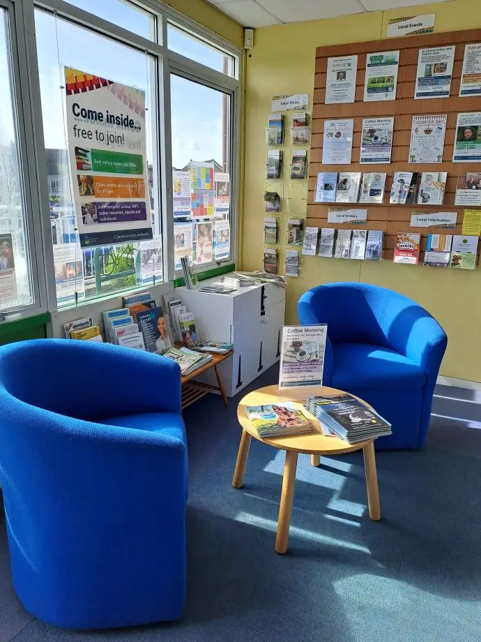 This is a picture of a small round table surrounded by two blue chairs.