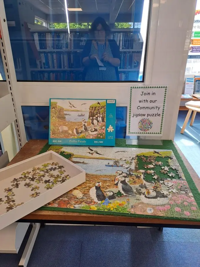 This is a picture of an unfinished jigsaw puzzle on a table.