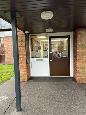 This is a picture of the entrance to Upton Library.  It has a door with letterbox on the left of picture and entrance door with large plastic handle on right.