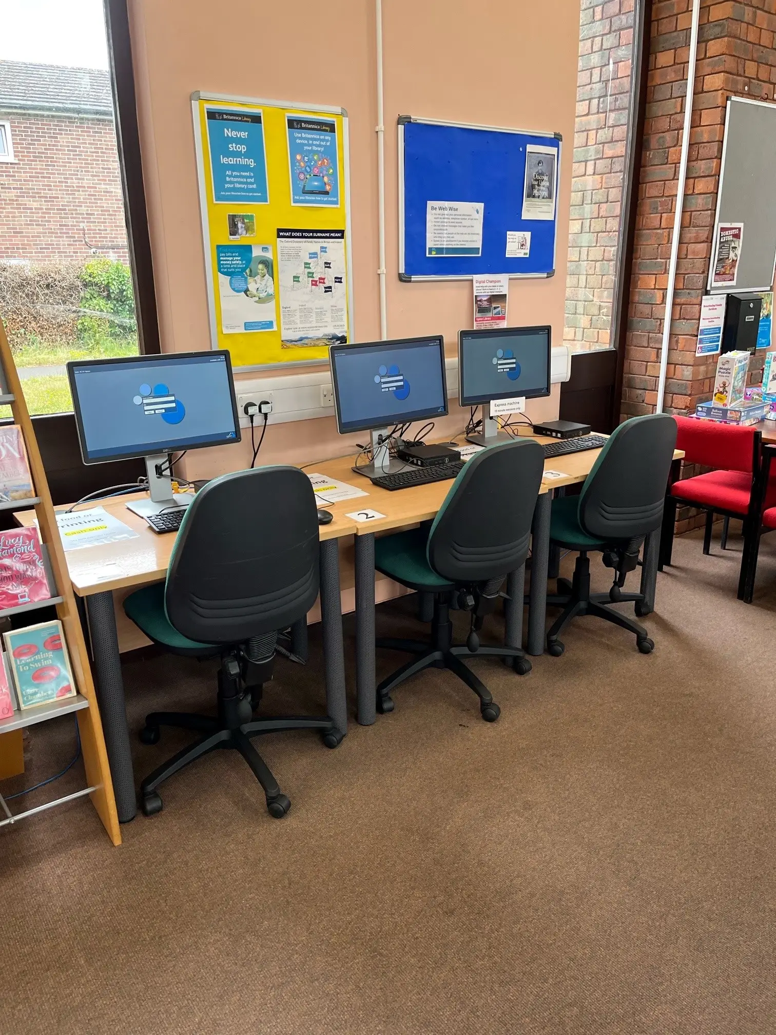 This is a picture of a table with three computer screens and keyboards.