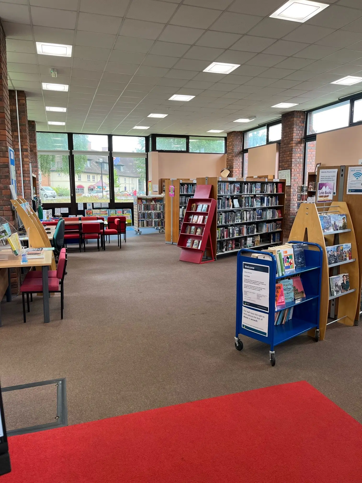 This is the picture of the library floor with tables and chairs and book shelves full of books.