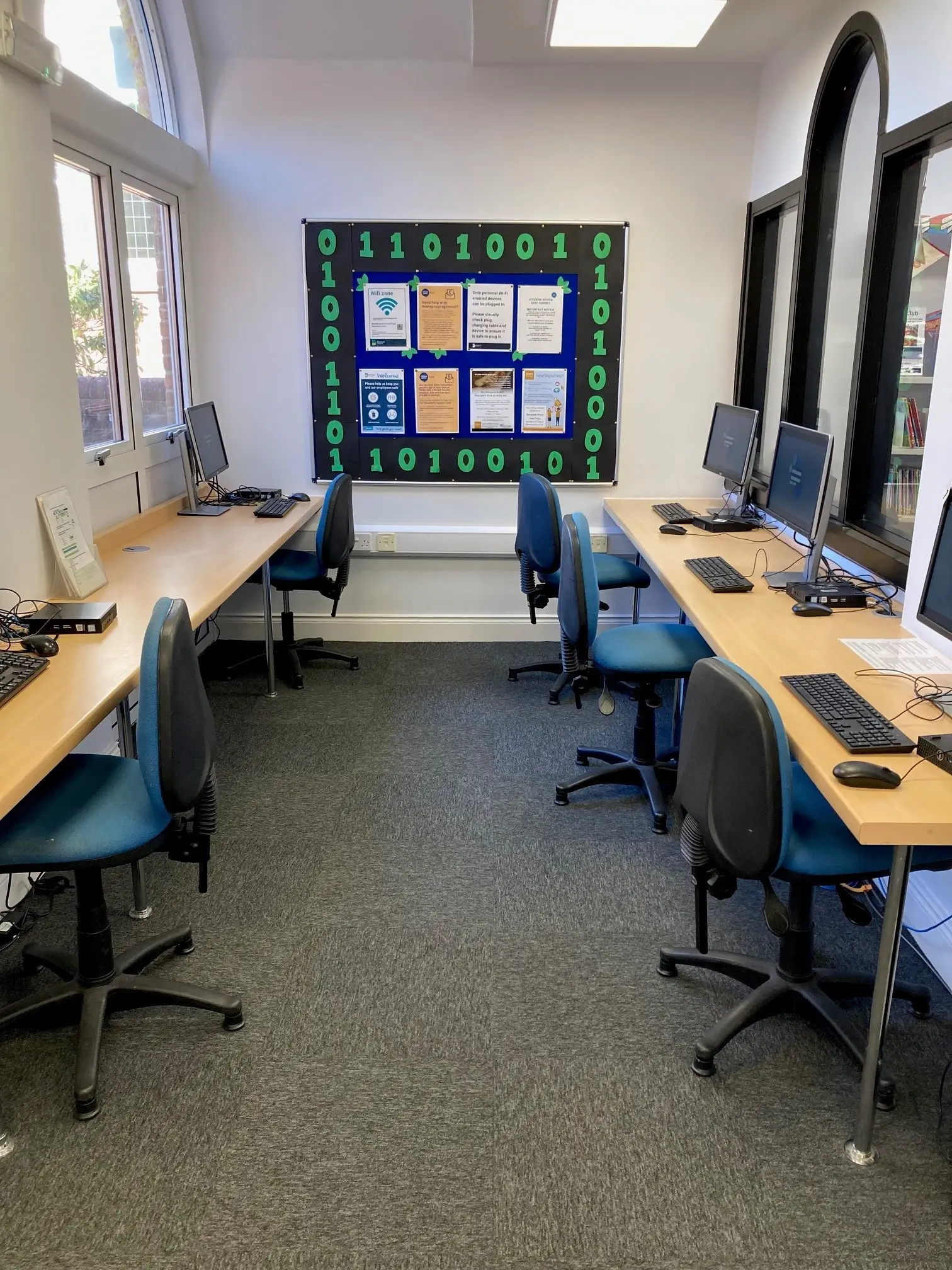 This is a picture of six desks with computer screens and keyboards on the and chairs in front.