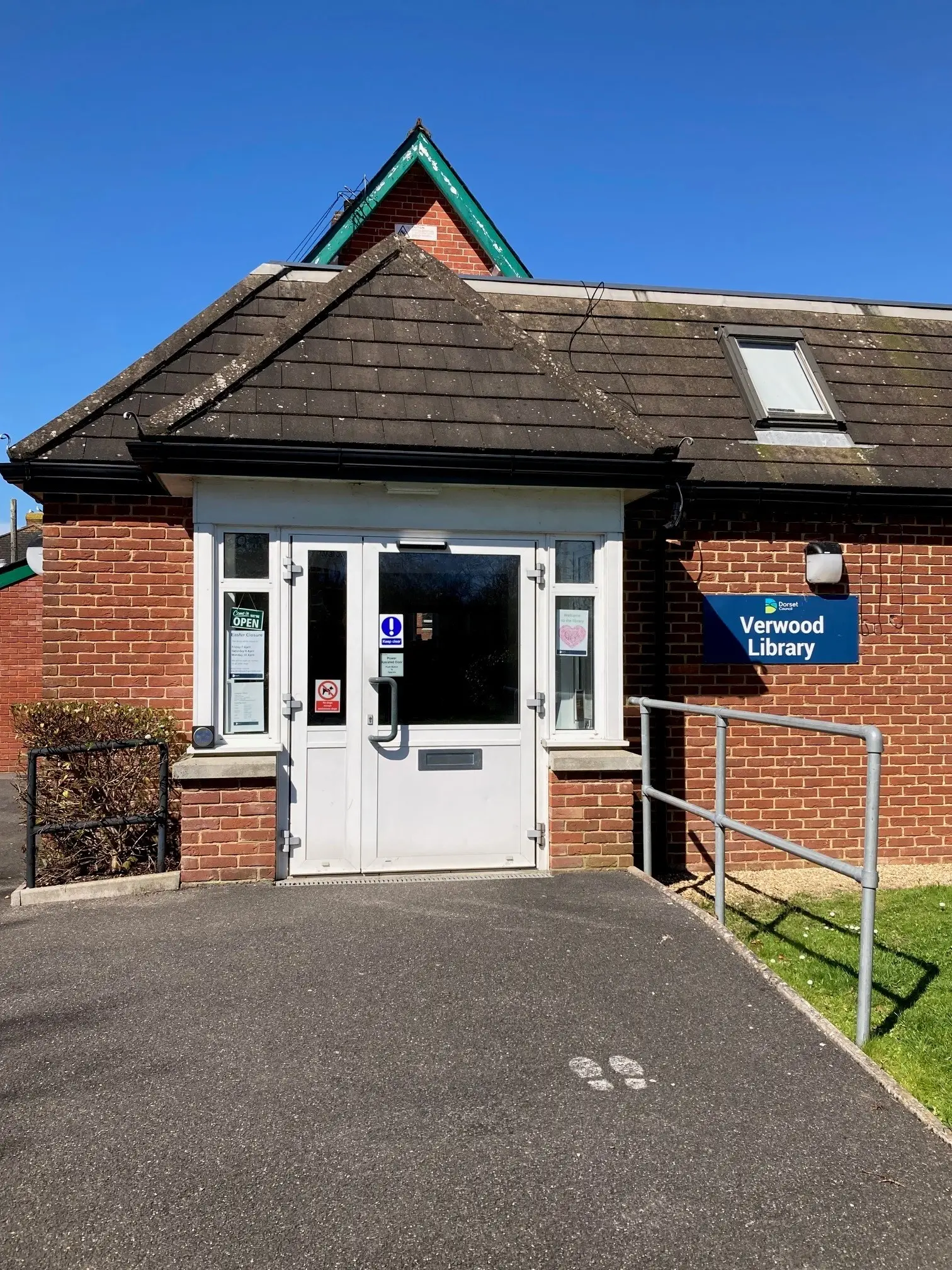 This is a picture of the entrance to Verwood Library, it has a white door with blue handle.