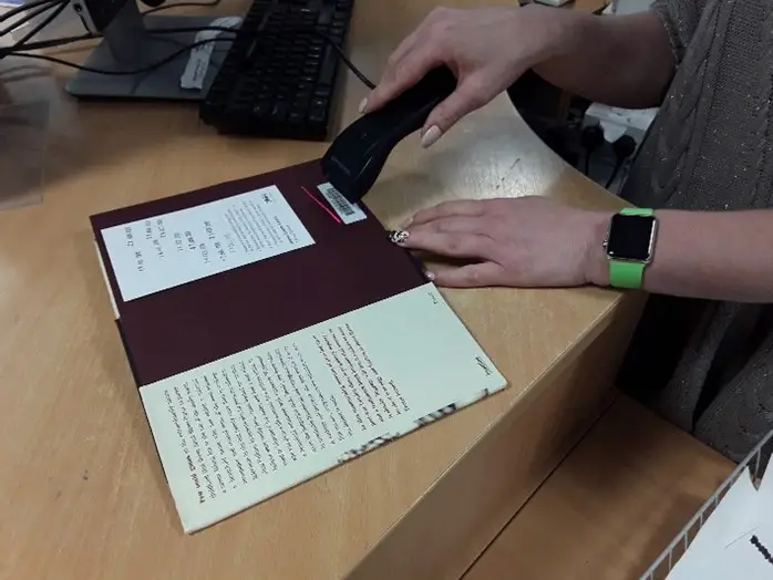 This is a picture of a library assistant scanning a book.