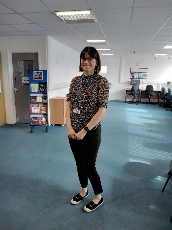 This is a picture of a library assistant standing smiling at the camera.