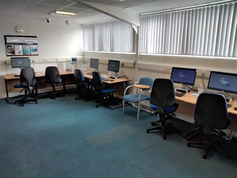 This is a picture of a three desks with two chairs in front of each and computer screens and keyboards on each desk.