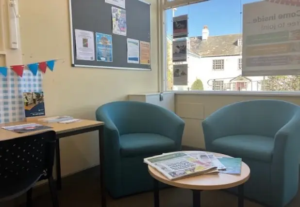 This is a picture of a small round table and two green chairs behind it.