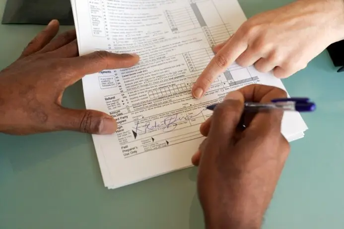 This is a picture of a person filling in an application form for library membership, hands only in the picture.