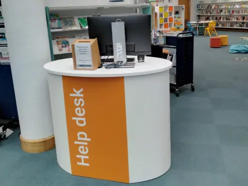 This is a picture of the help desk in the library with a computer screen.