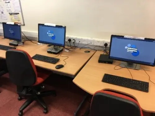 This is an image of desks with three computer screens with keyboards.