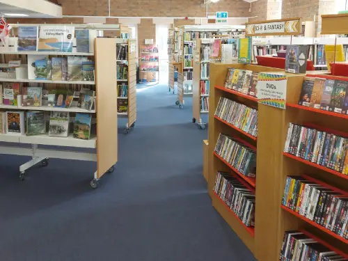 This is an image of shelving units.  The units to the left contain books and the ones to the right contain dvds.