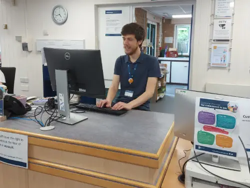 This is an image of a library assistant behind the front desk working behind a computer screen on a keyboard.