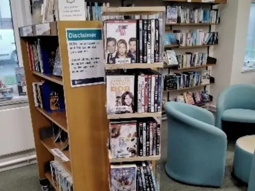 This is an image of a shelve of DVDs with two chairs in the background.