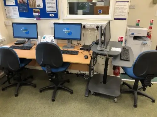 This is an image of a table with two computer screens, keyboards and chairs in front.