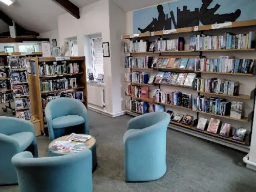 This is an image of four blue chairs around a small round table with shelves of books behind.