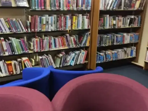 This is an image of four chairs in the foreground and shelves of books behind.