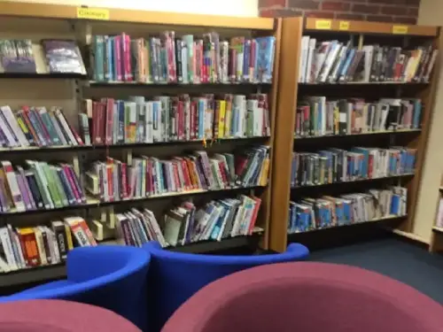 This is an image of four chairs in the foreground and shelves of books behind.