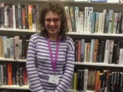 This is an image of a library assistant standing and smiling at the camera.