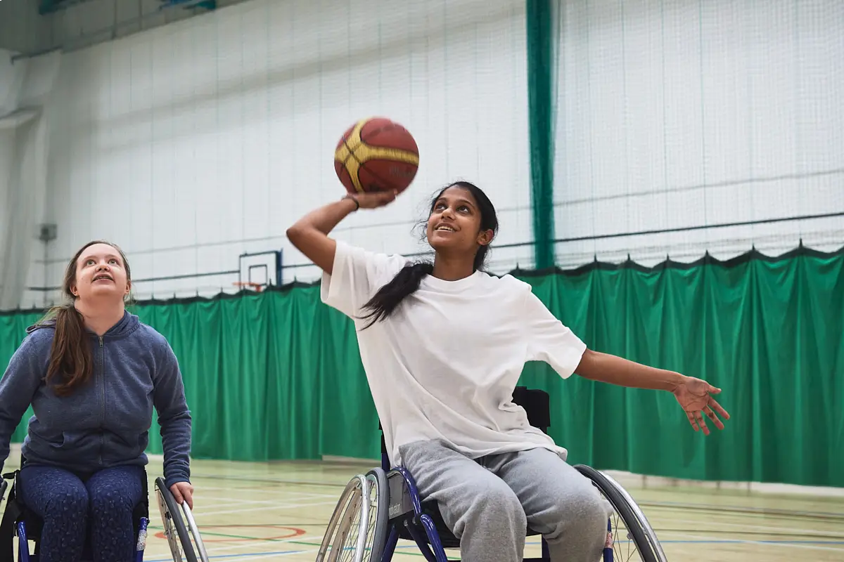 Two teenage girls playing wheelchair basketball