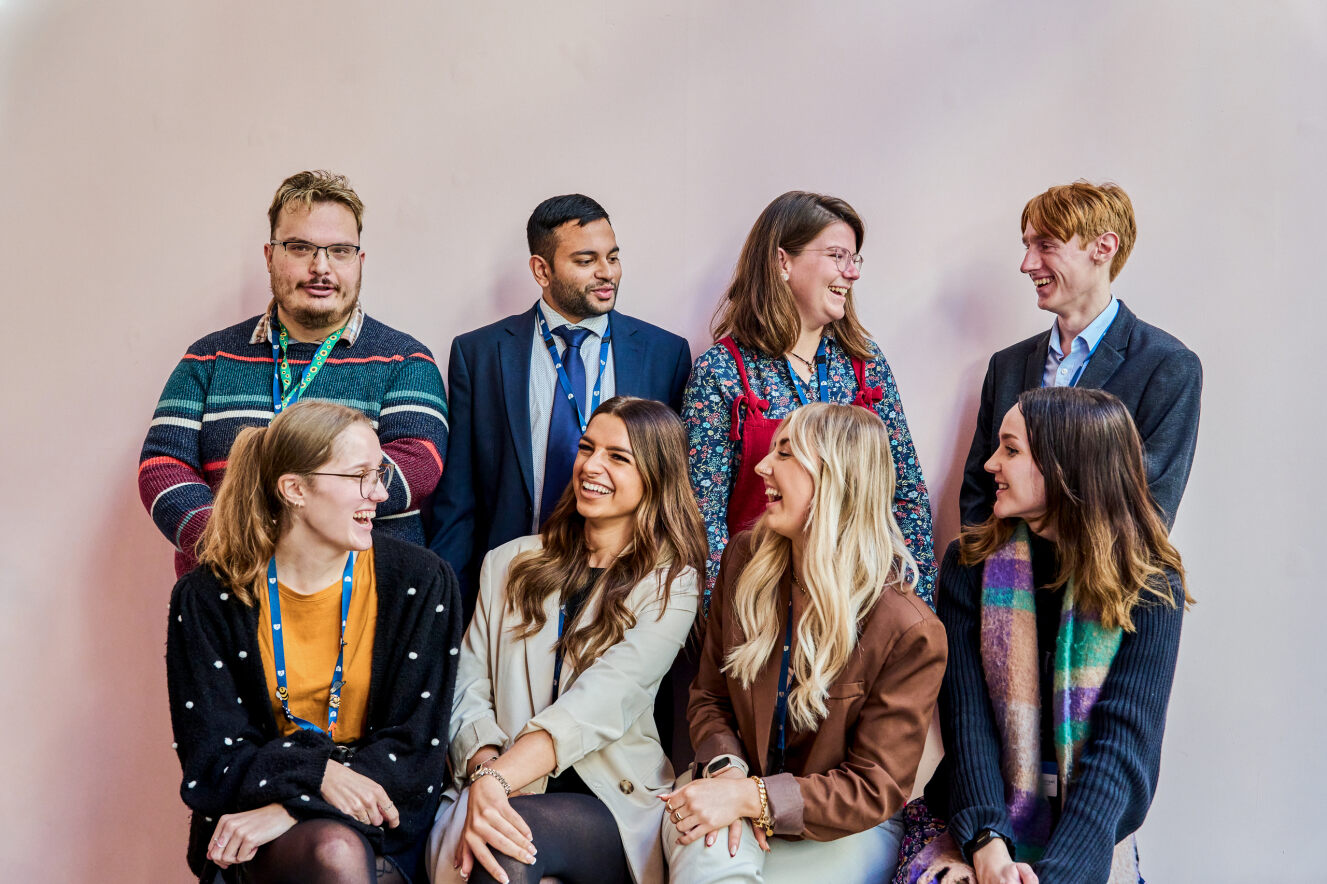 Group of people sitting and standing for a photoshoot.
