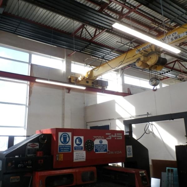 Industrial workspace at Canford Manufacturing with a red AMADA PEGA 345 machine and a yellow overhead crane