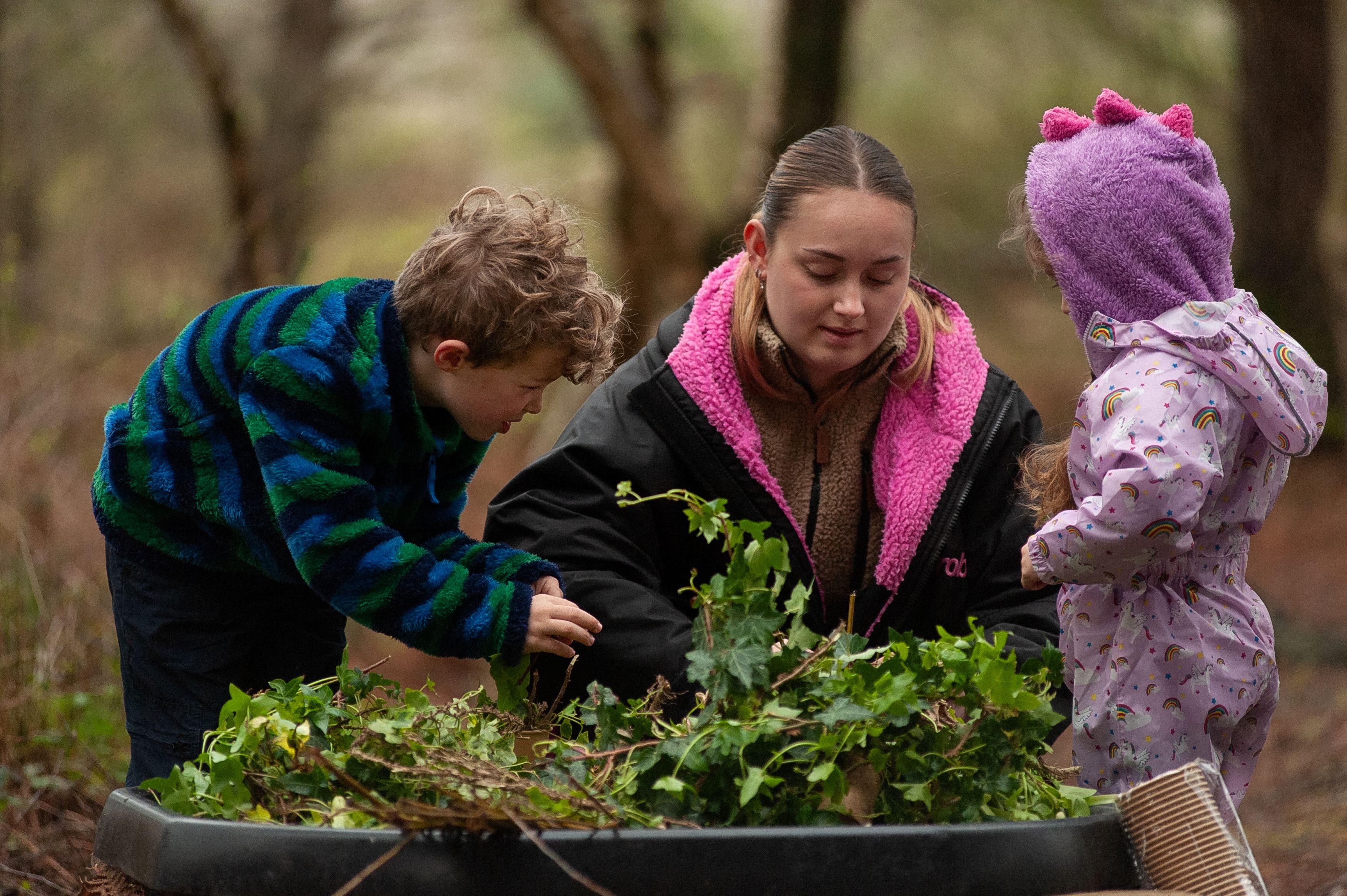 Woman and two young children foraging in the woods
