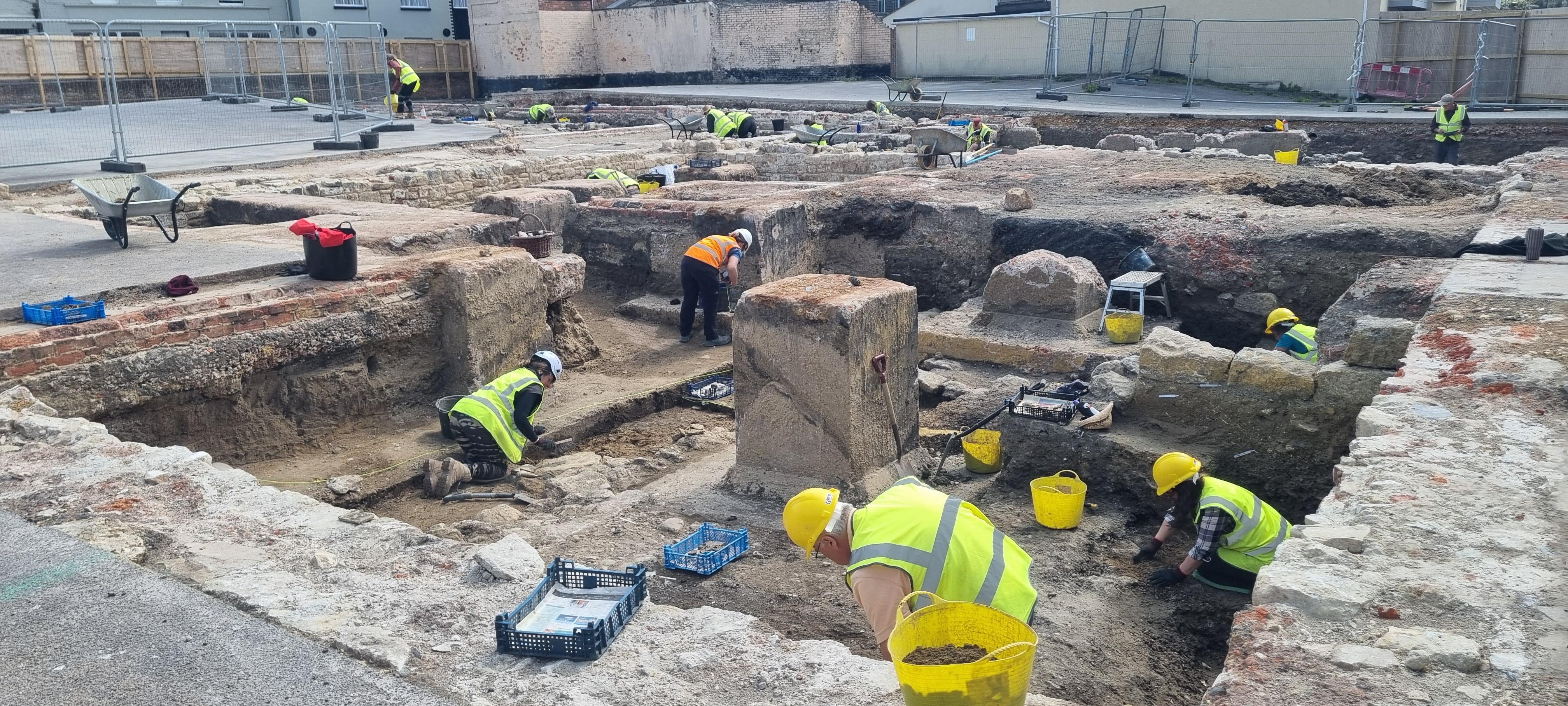 The archaeological dig at the former Weymouth Bowl site in Weymouth. People in hard hats and high vis jackets taking part in the dig.