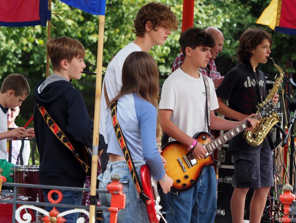 the image shows 5 young people playing instruments on a stage.