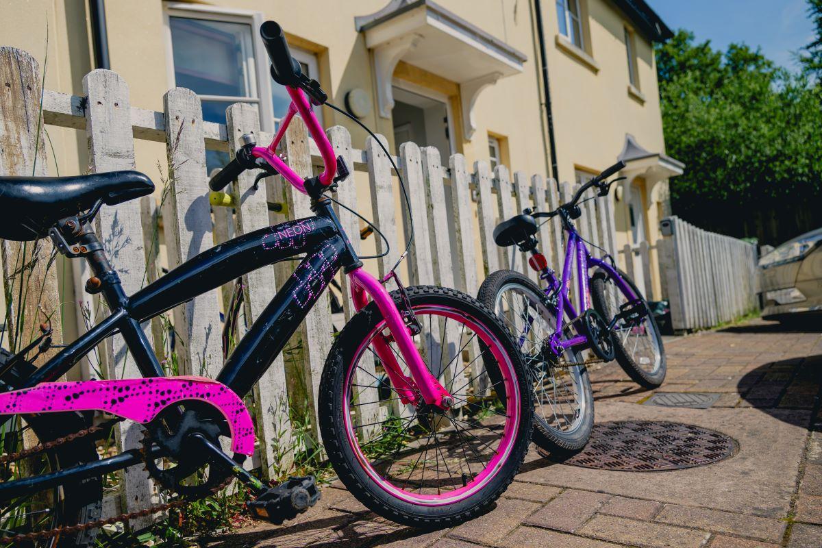 This is an image of children&#39;s bikes up against a fence outside of affordable housing in Dorset