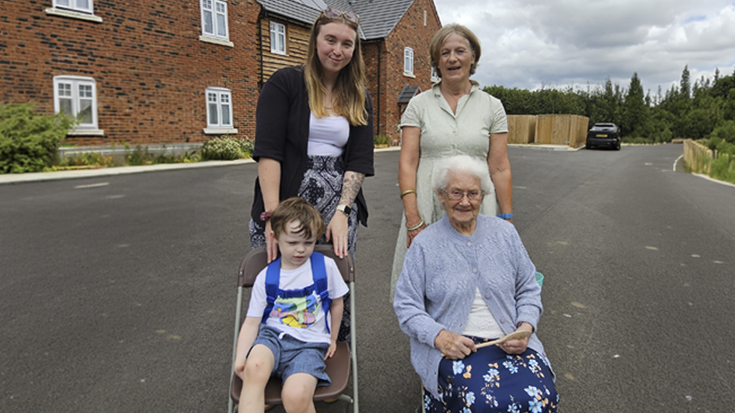 Three white female Fiddleford residents of three generations with a small boy stood next to new build homes
