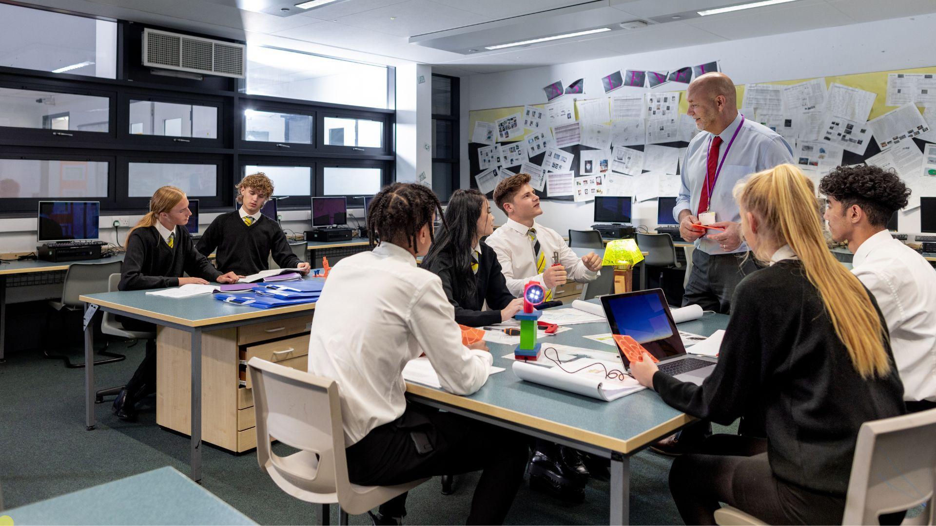 teenagers seated in a classroom with a teacher standing