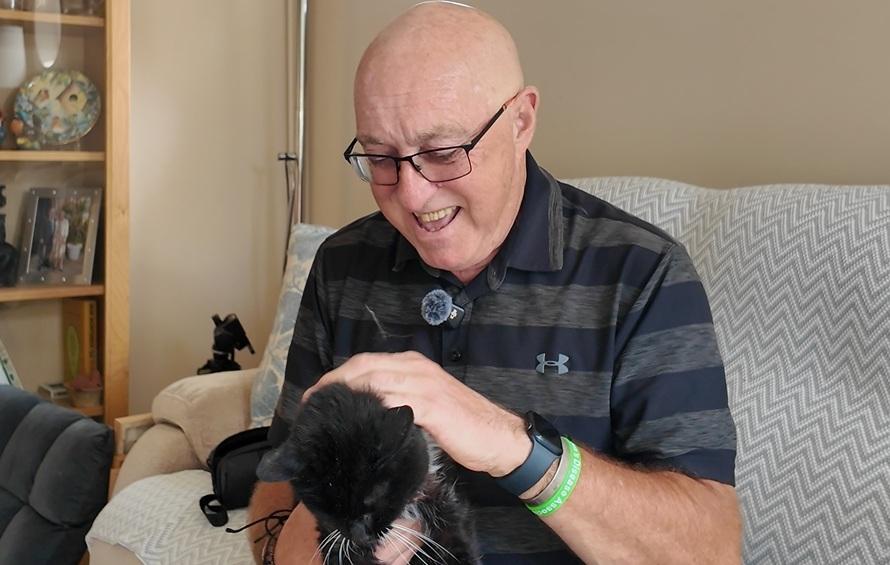 this shows a man petting a cat on his lounge in a sitting room