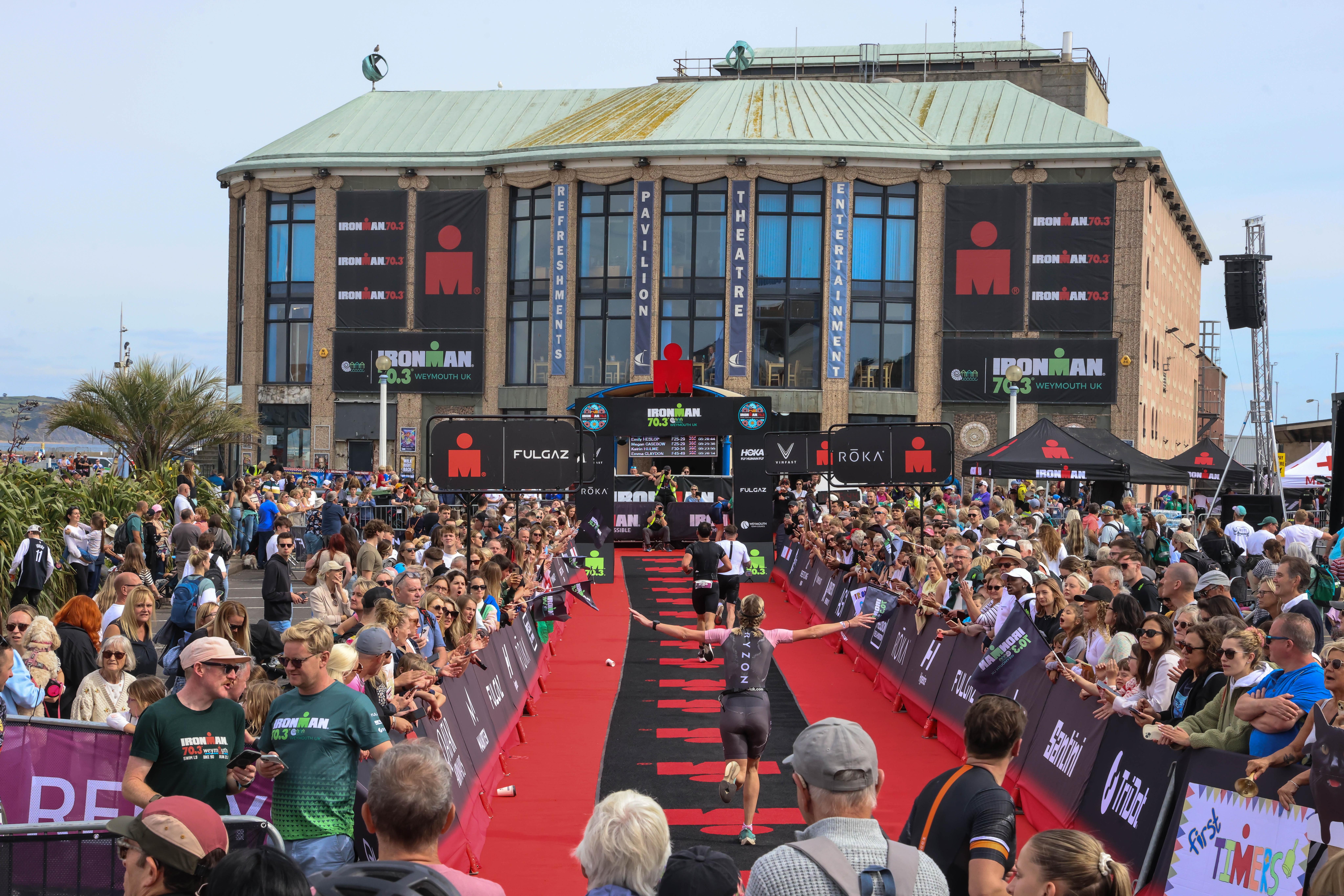 Runners on the red carpet approaching Weymouth Pavilion surrounded by crowds of people
