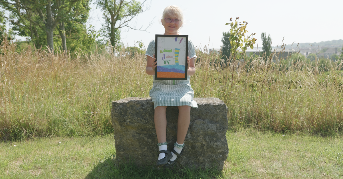 Girl sat on a stone showing a picture of